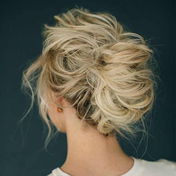 a gorgeous messy chignon with messy volume on top, locks down and a bold rhinestone hairpiece