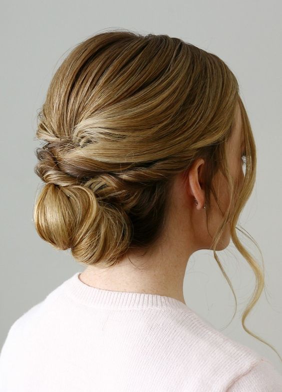 a twisted low bun on long hair and a bump on top for a chic modern bridal look