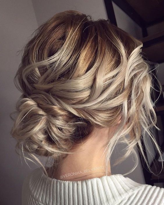 a low bun with a side braid and a bump for a whimsy take on a usual low bun hairstyle