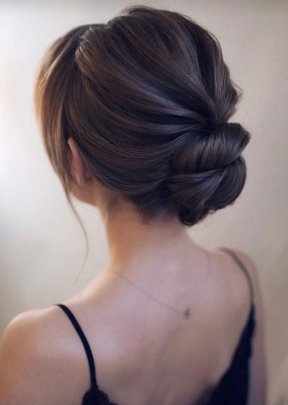 an elegant and effortless twisted low bun with a bump and some locks plus messy details