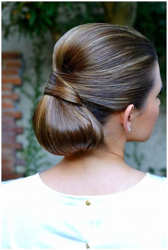 a low messy chignon hairstyle with a bump and much texture for a chic look plus a clear ribbon bow
