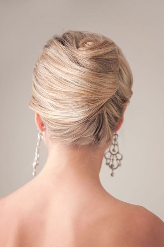 a textural low chignon hairstyle with a bump, bangs and a rhinestone hairpiece for an accent