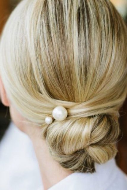 an elegant messy low updo with textures and a small rhinestone hairpiece to look effortlessly chic