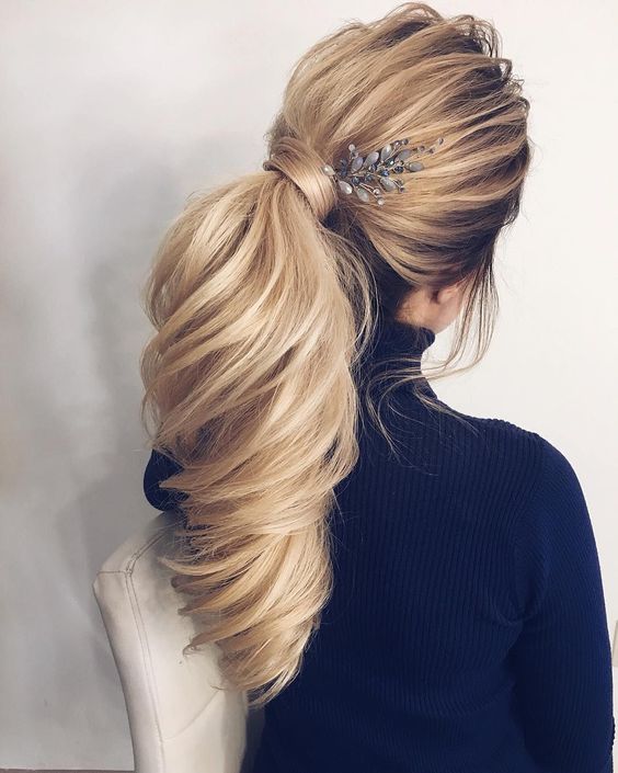 a chic twisted side low ponytail with bangs and a ribbon for an accent is ideal for a modern wedding