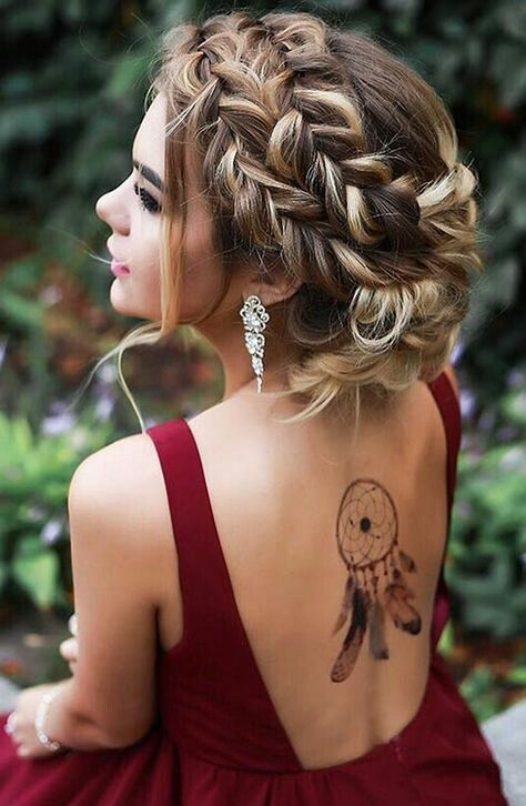 a braided low updo with a volume and some locks plus a rhinestone hairpiece