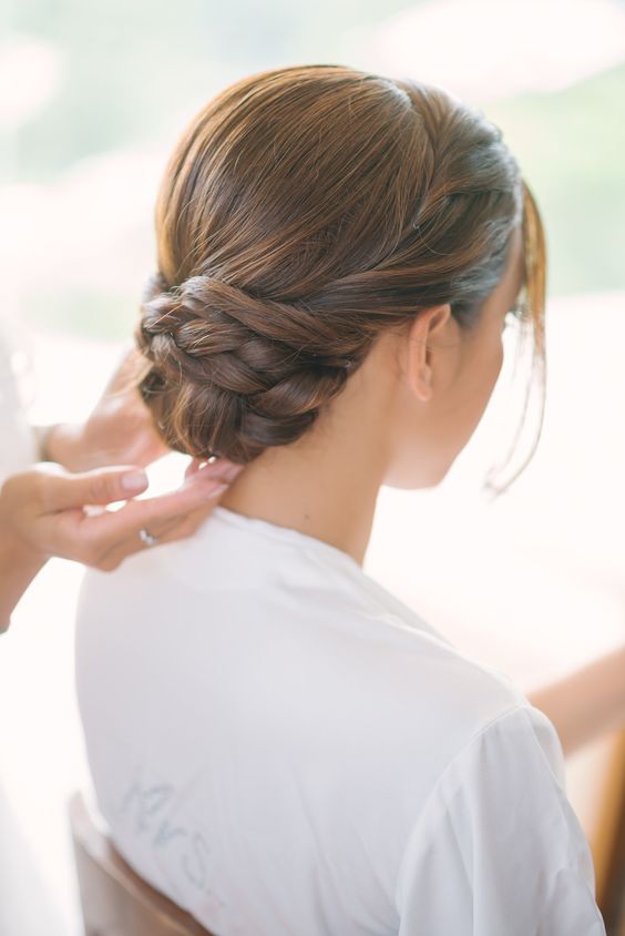 a messy and wavy updo with a large fishtail braid in the center and locks down