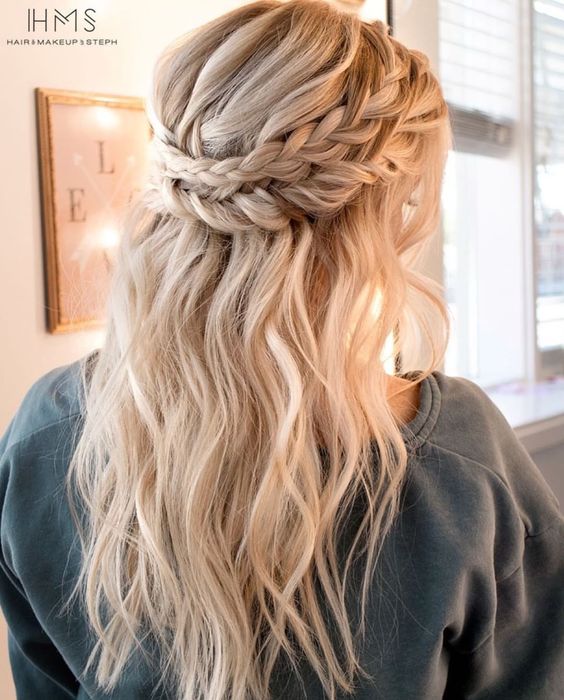 a half updo with a halo braid and waves accented with a hair vine for a boho bride