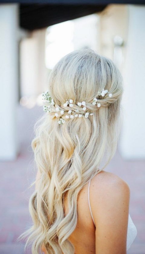 a wavy and twisted side half updo accessorized with a fresh flower crown
