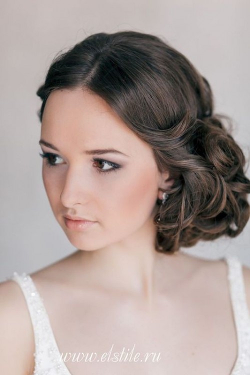 a side knot accented with a braid and a sleek top and a white floral hairpiece is a romantic option