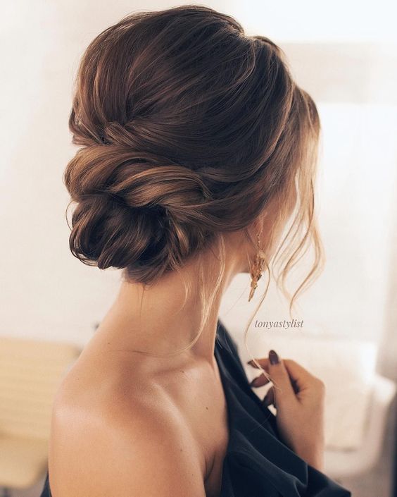 a diagonal braided updo with a low bun, some locks down and a little hairpiece