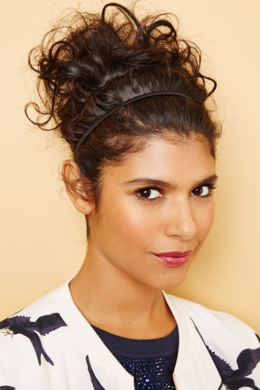 an updo with a sleek top and a braided and curly low bun plsu fresh blooms as an accent