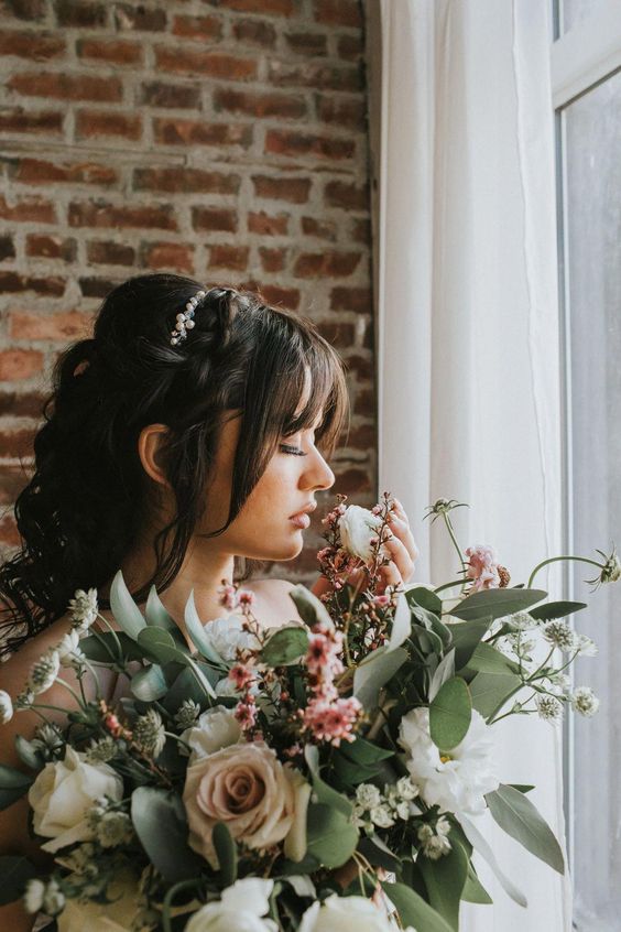 a side curl wedding hairstyle with a bang looks luxurious and vintage-inspired