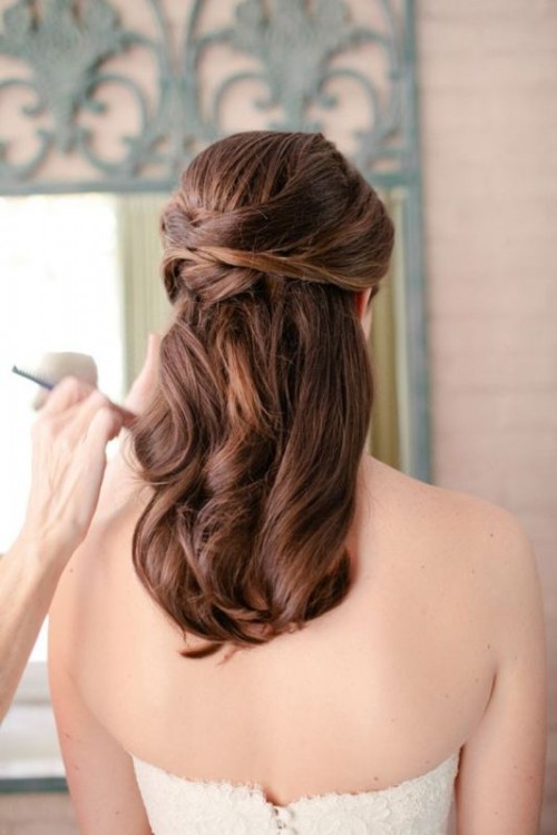 a chic yet relaxed wedding half updo with a volume on top, side bangs, a braided halo and waves down is very romantic