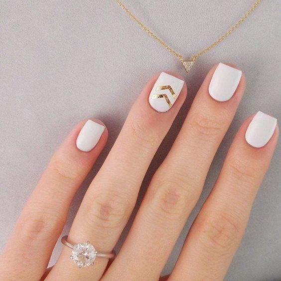 a white manicure with a gold glitter chevron and a gold glitter accent nail is a very elegant and fresh option